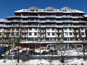 Ett hotell med flera våningar, en symmetrisk fasad, balkonger och en skylt som visar att det finns en skidort i närheten.