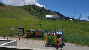 Vista de una ladera verde con un edificio pequeño y una estructura inflable de colores.