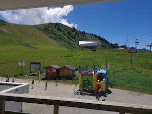 A view of a green hillside with a small building and a colorful inflatable play structure.