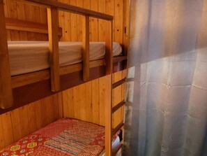 A bunk bed room with wooden walls and a metal curtain.