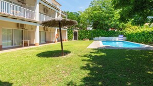 Ein Hotel mit Schwimmbad, überdachter Terrasse und gepflegtem Rasen.