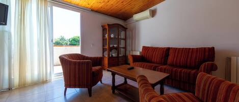 A living room with a wooden ceiling, a sofa, a chair, a cabinet, and a table.