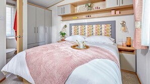 Ein Schlafzimmer mit Bett, Nachttischen, einem Kleiderschrank und einem Kopfteil mit geometrischen Mustern.
