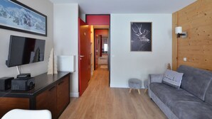 Een moderne woonkamer met een grijze bank, een flatscreen televisie, een houten kast en een lijst met een foto van een hert.