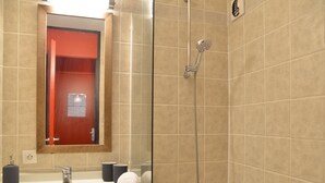Een badkamer met een wastafel, spiegel, handdoek en douche.