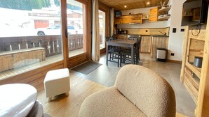 Ein gemütliches Blockhaus-Interieur mit Essbereich, Küche und einem Balkon mit Blick auf ein Fahrzeug und Gebäude.