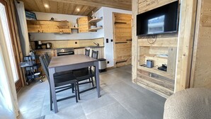 Eine moderne Küche mit Holzschränken, einem Esstisch und einem integrierten Fernseher.