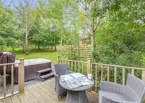 A wooden deck with wicker furniture, a hot tub, and a wooden fence.