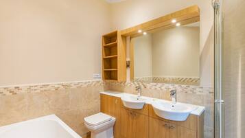 A bathroom with a bathtub, two sinks, a toilet, and a shower.