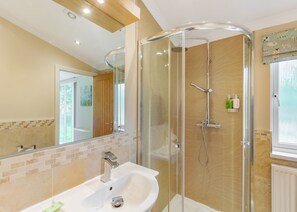 A modern bathroom with a glass-enclosed shower, a white sink, and a mirror.