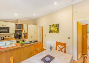 A compact kitchen with modern appliances, a dining area with a wooden table and chairs, and a painting on the wall.