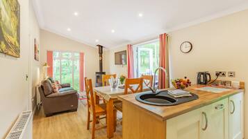 A cozy kitchen with a dining area, wooden furniture, a built-in stove, and a view of greenery outside.
