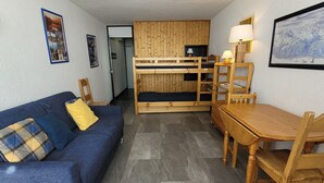 Ett litet rum med en våningssäng, en soffa, ett matbord och stolar.
