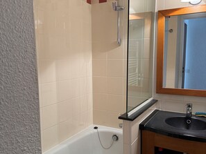 Uma casa de banho com banheira, pia e espelho.