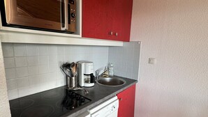 Una cocina compacta equipada con microondas, cafetera y lavavajillas.