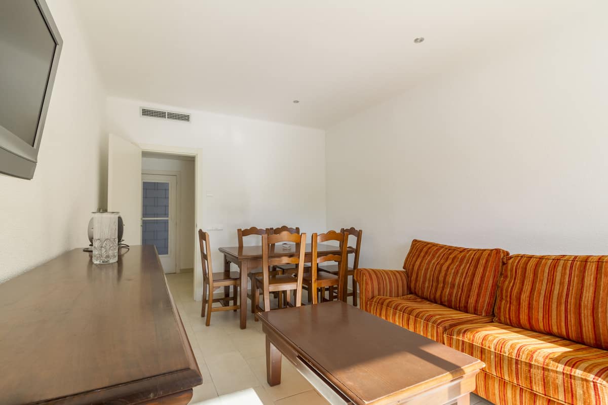 Una sala de estar con una mesa de comedor de madera, sillas y un sofá a rayas.