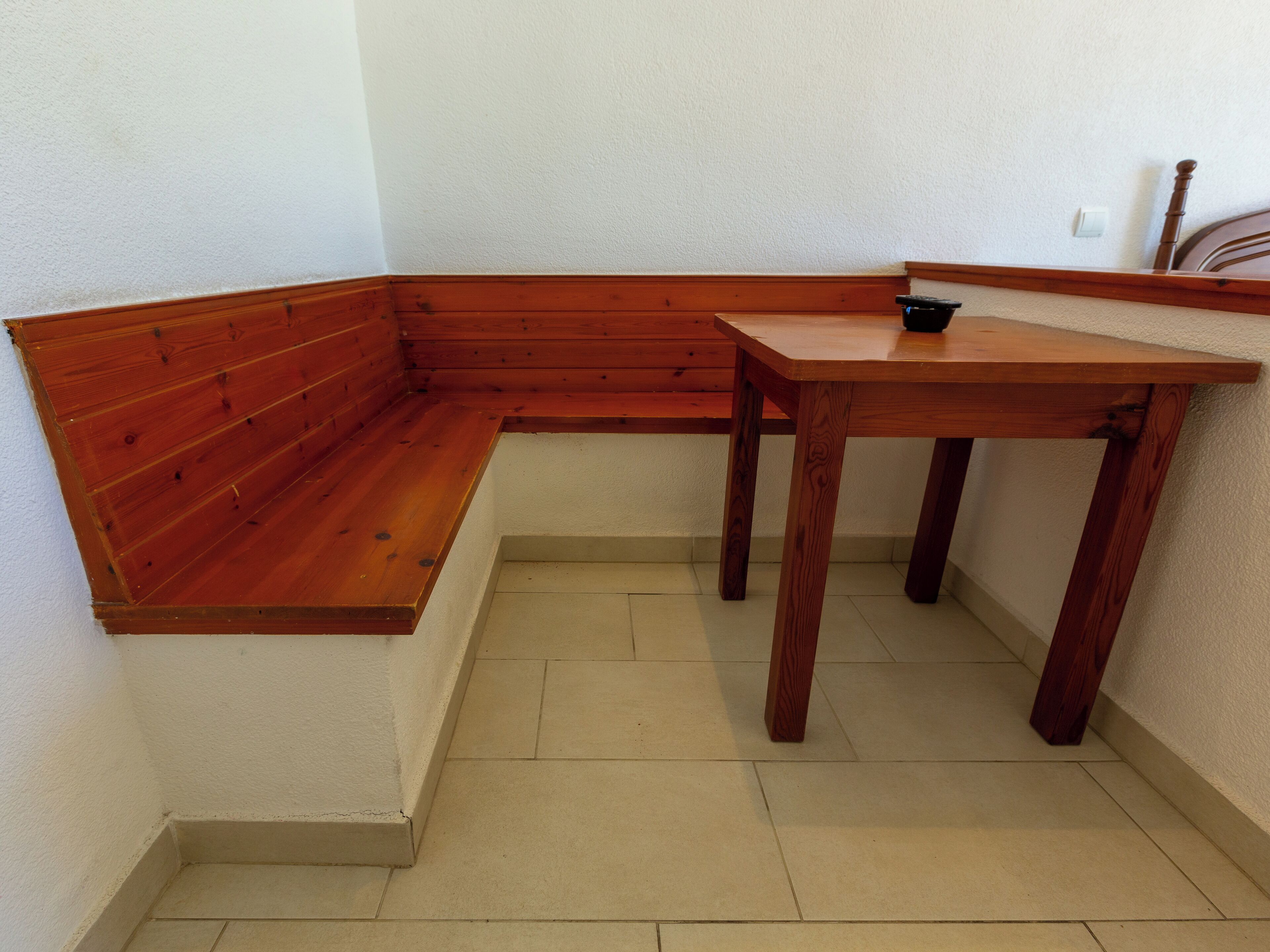 Een hoekzaal met een houten bankje en een klein tafeltje.