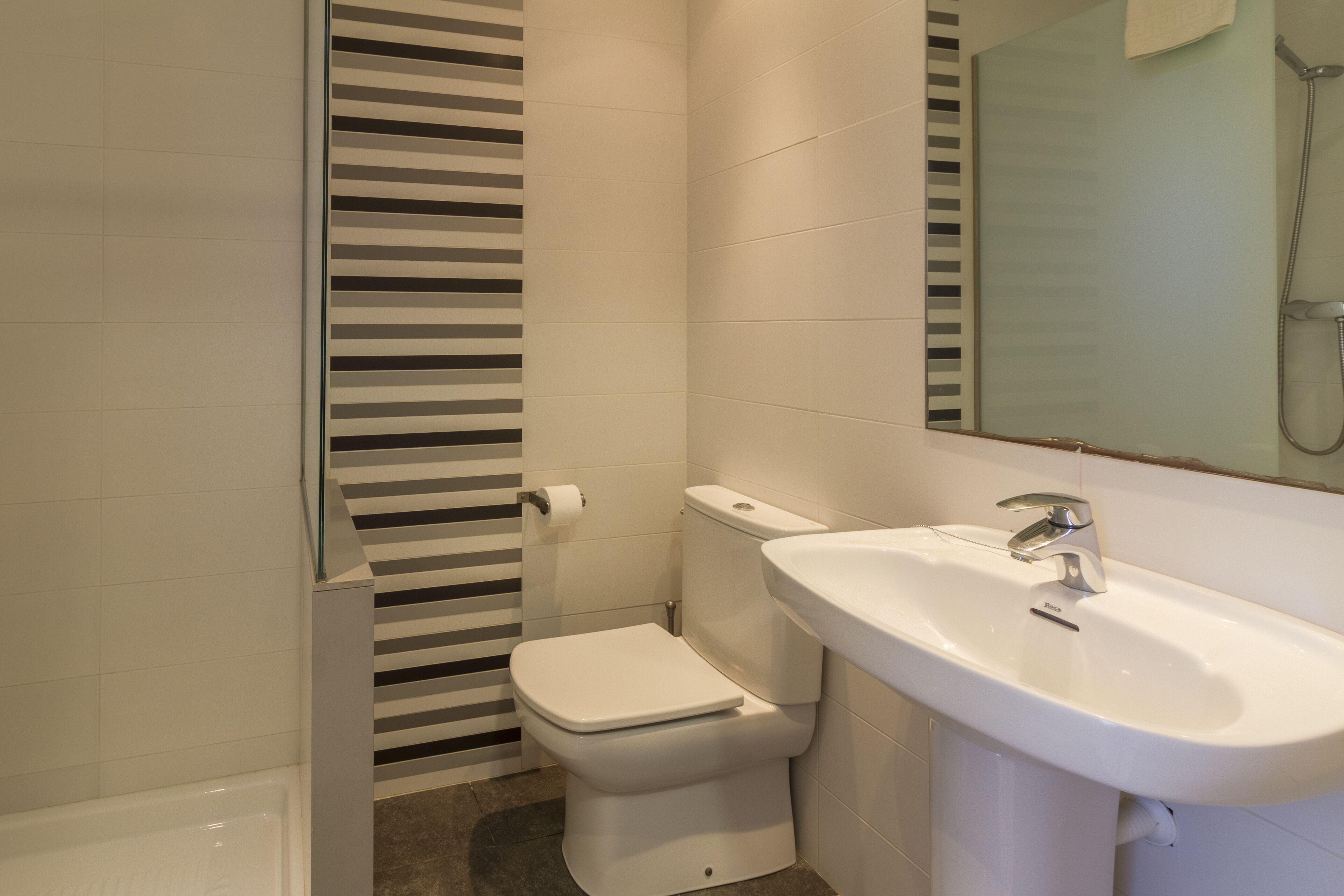 A bathroom with a toilet, sink, and shower.