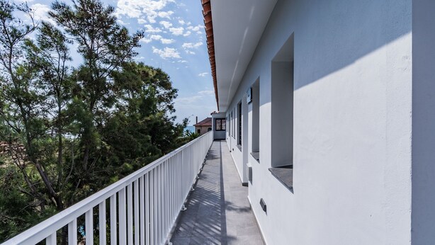 A balcony with a white railing, overlooking a row of windows and a tree-lined street. - SUNWAY SAN JORGE (Sitges)