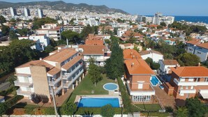 An aerial view of a residential area with multiple buildings, a swimming pool, and a clear view of the sea. - SUNWAY SAN JORGE (Sitges)