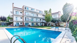 A swimming pool with a metal ladder, surrounded by a multi-story building with balconies and outdoor seating areas. - SUNWAY SAN JORGE (Sitges)