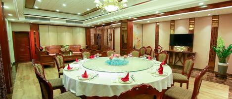 A dining area with a round table, chairs, and a chandelier.
