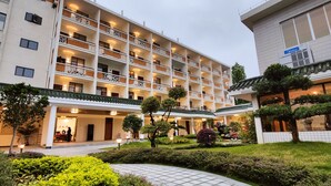 A multi-story hotel with a traditional architectural style, featuring a courtyard with well-maintained greenery and a tiled pathway. - White Swan Guest House (Zhaoqing)