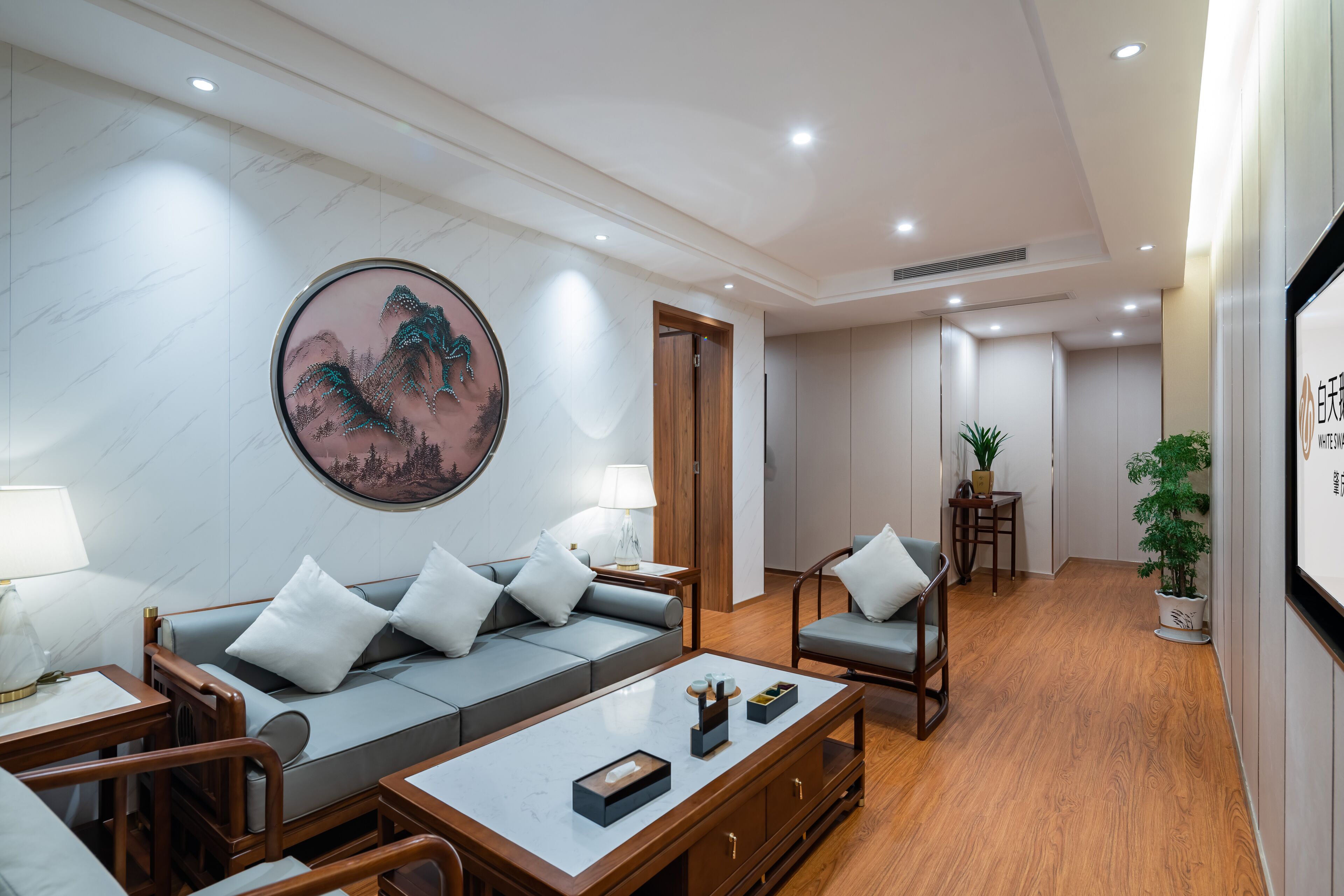 A modern living room with a sofa, armchairs, a coffee table, and a wall-mounted painting.