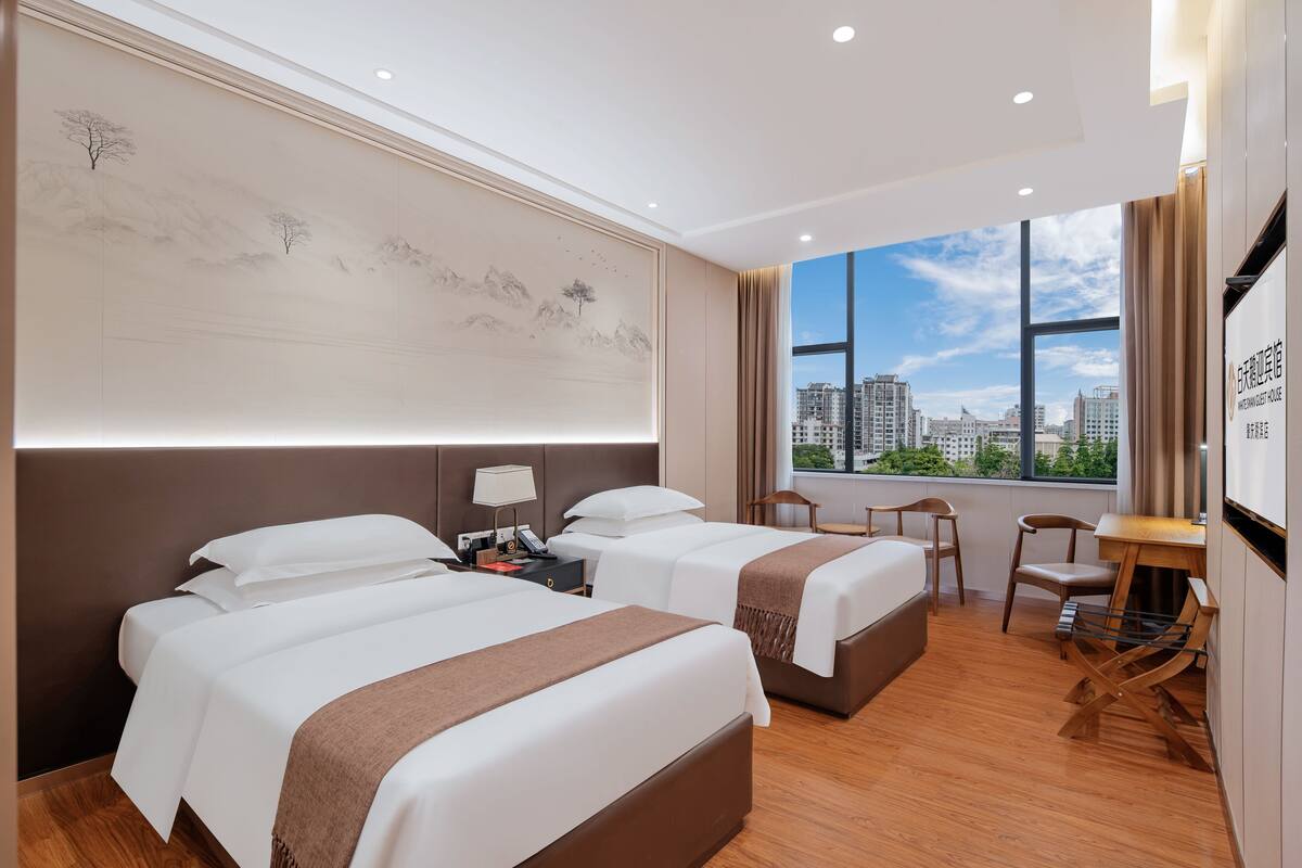 Une chambre d’hôtel avec deux lits, un bureau et une vue sur la ville.
