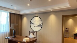 A hotel room with a wooden desk, a lamp, a painting, and a wardrobe. - White Swan Guest House (Zhaoqing)