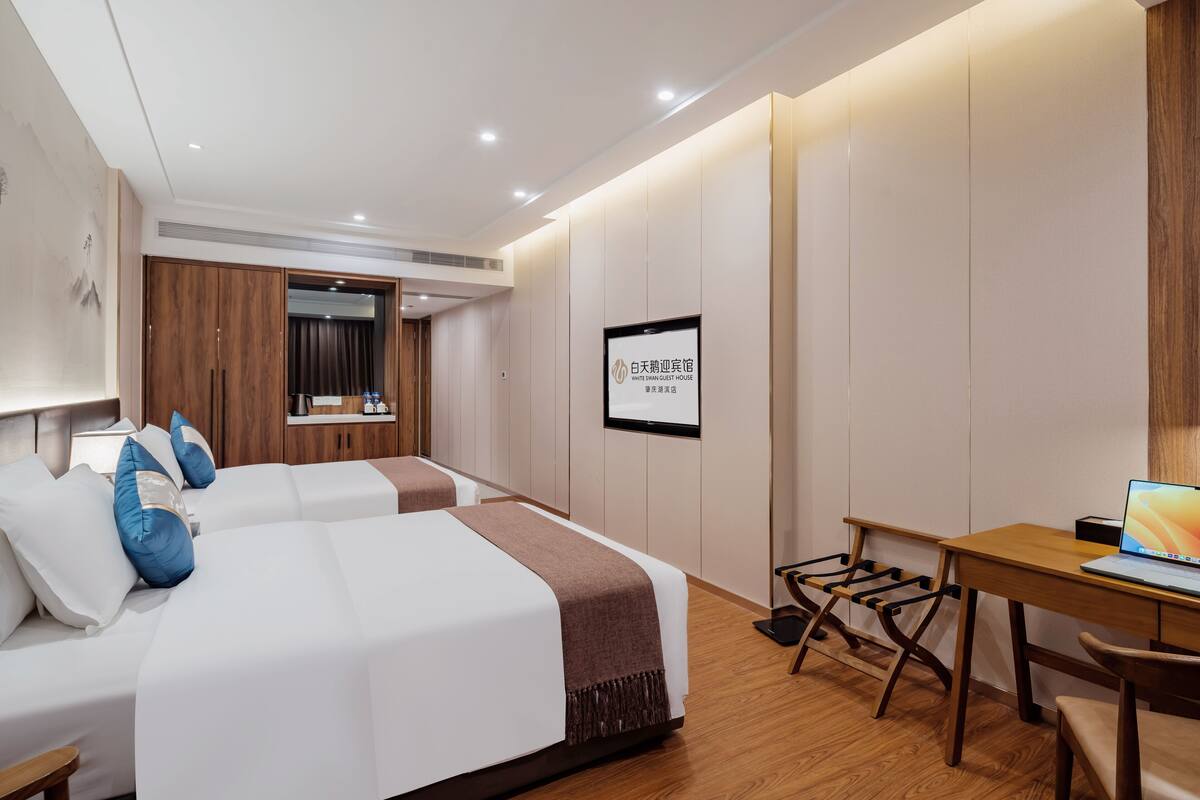 Une chambre d’hôtel avec deux lits, un bureau et une chaise.