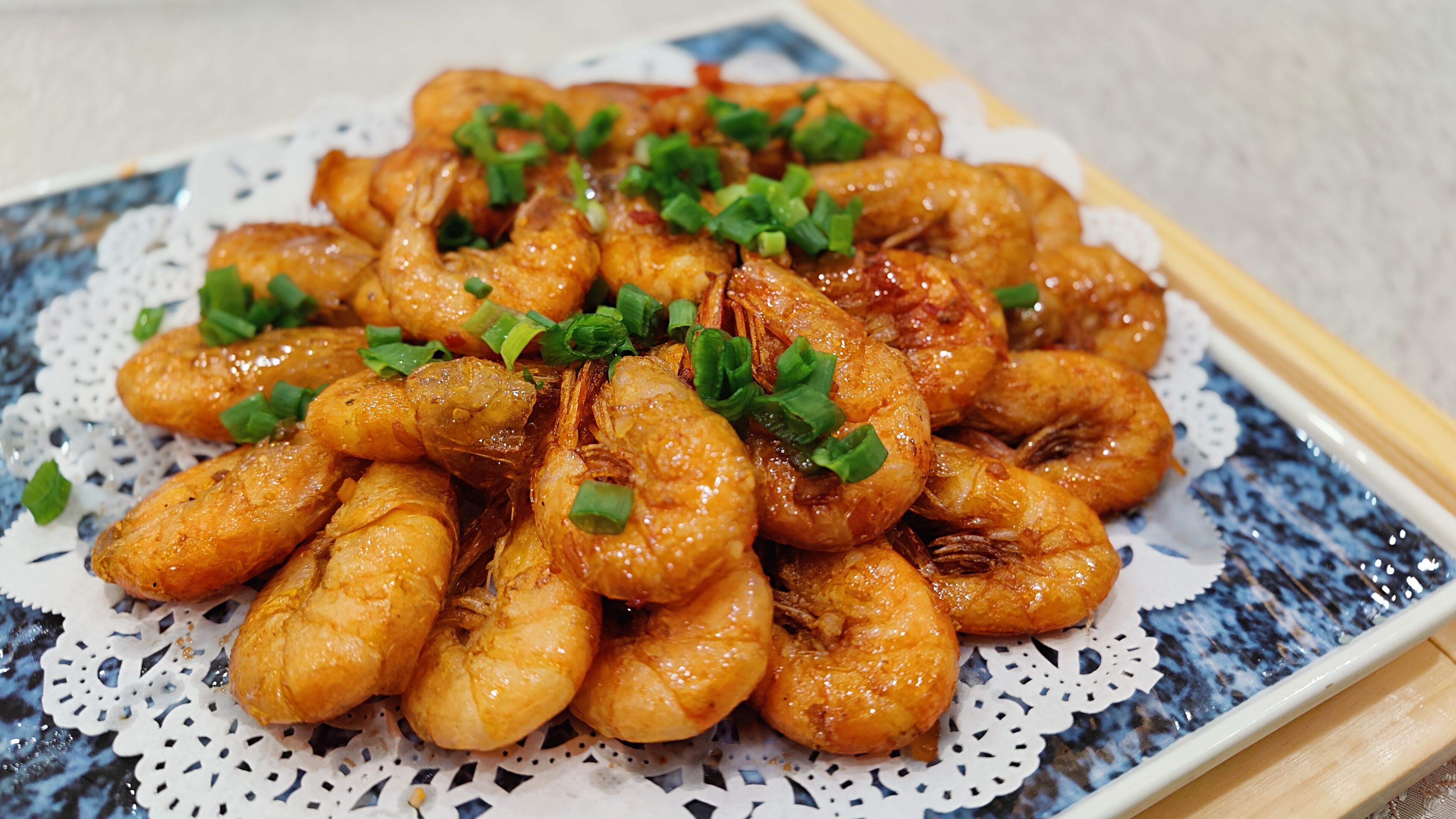 A plate of cooked shrimp garnished with chopped green onions.
