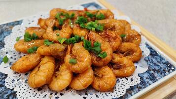 A plate of cooked shrimp garnished with chopped green onions.