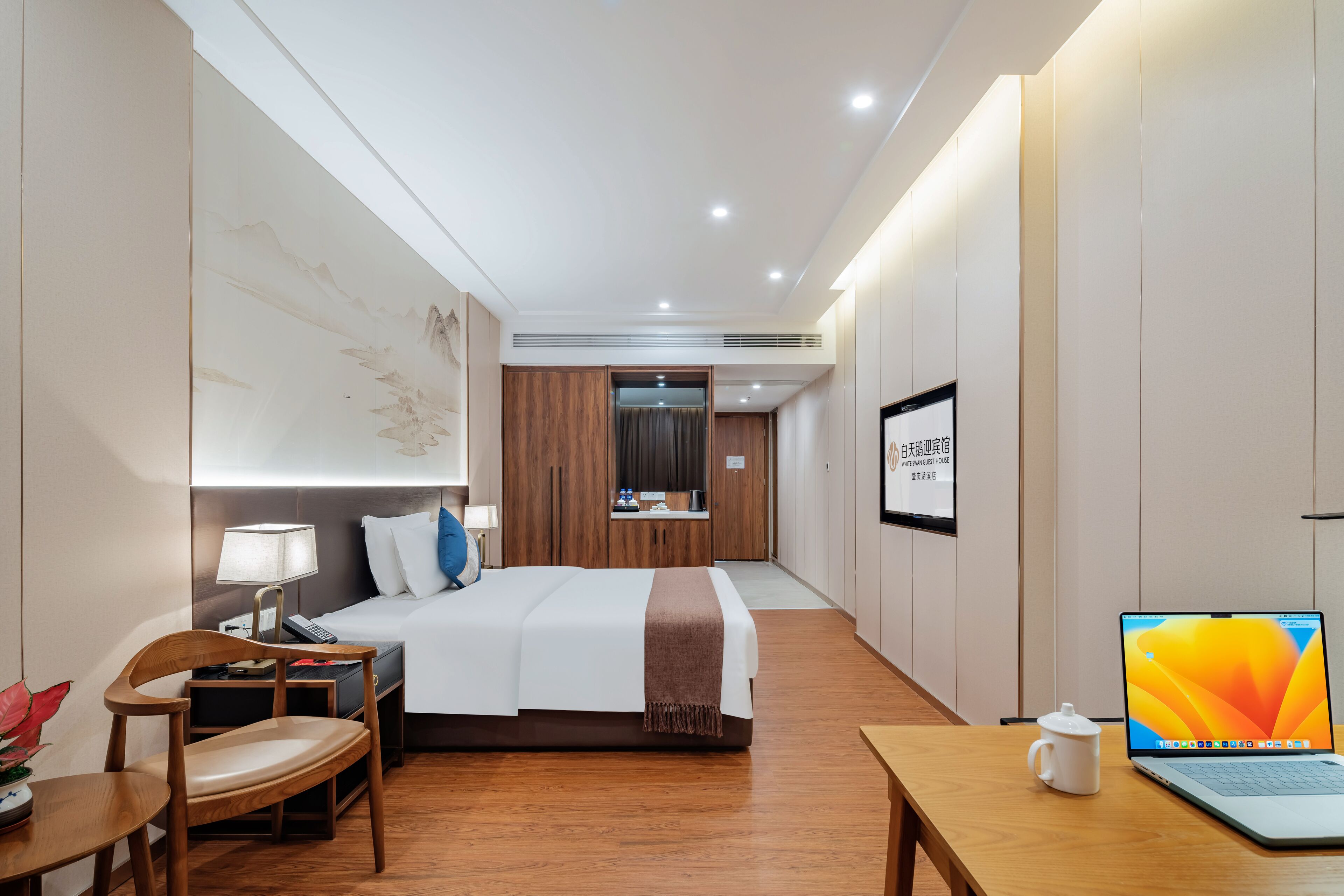 Una habitación de hotel con cama, mesita de noche, silla, escritorio y una computadora portátil.