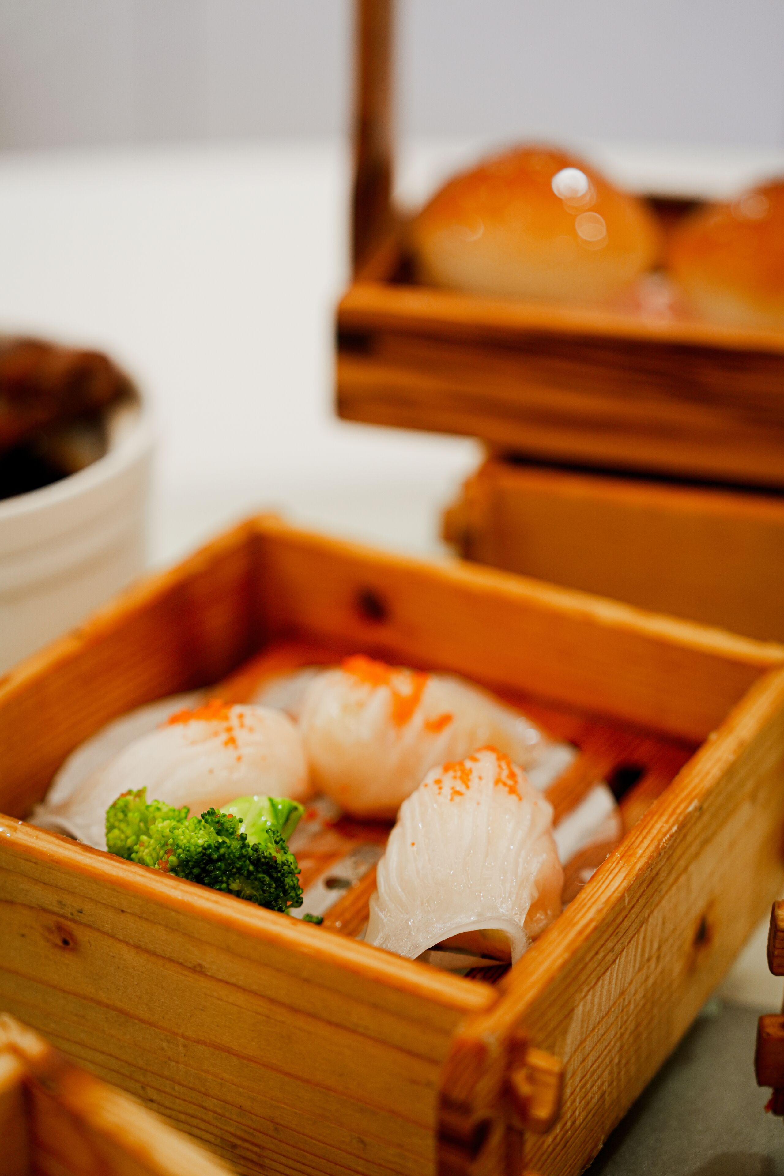 A wooden tray with sushi and a piece of broccoli.