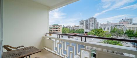 A balcony with a table and chairs, offering a view of a cityscape with buildings and trees.
