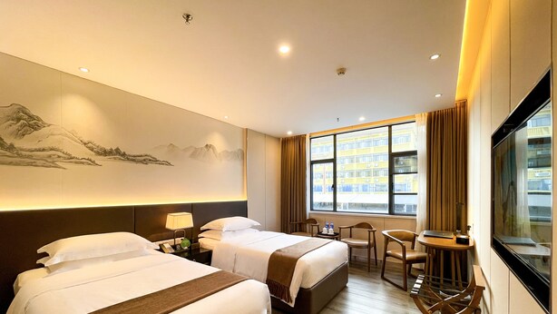 A hotel room with two beds, a desk, chairs, a large window with a view of buildings, and a painting on the wall. - White Swan Guest House (Zhaoqing)