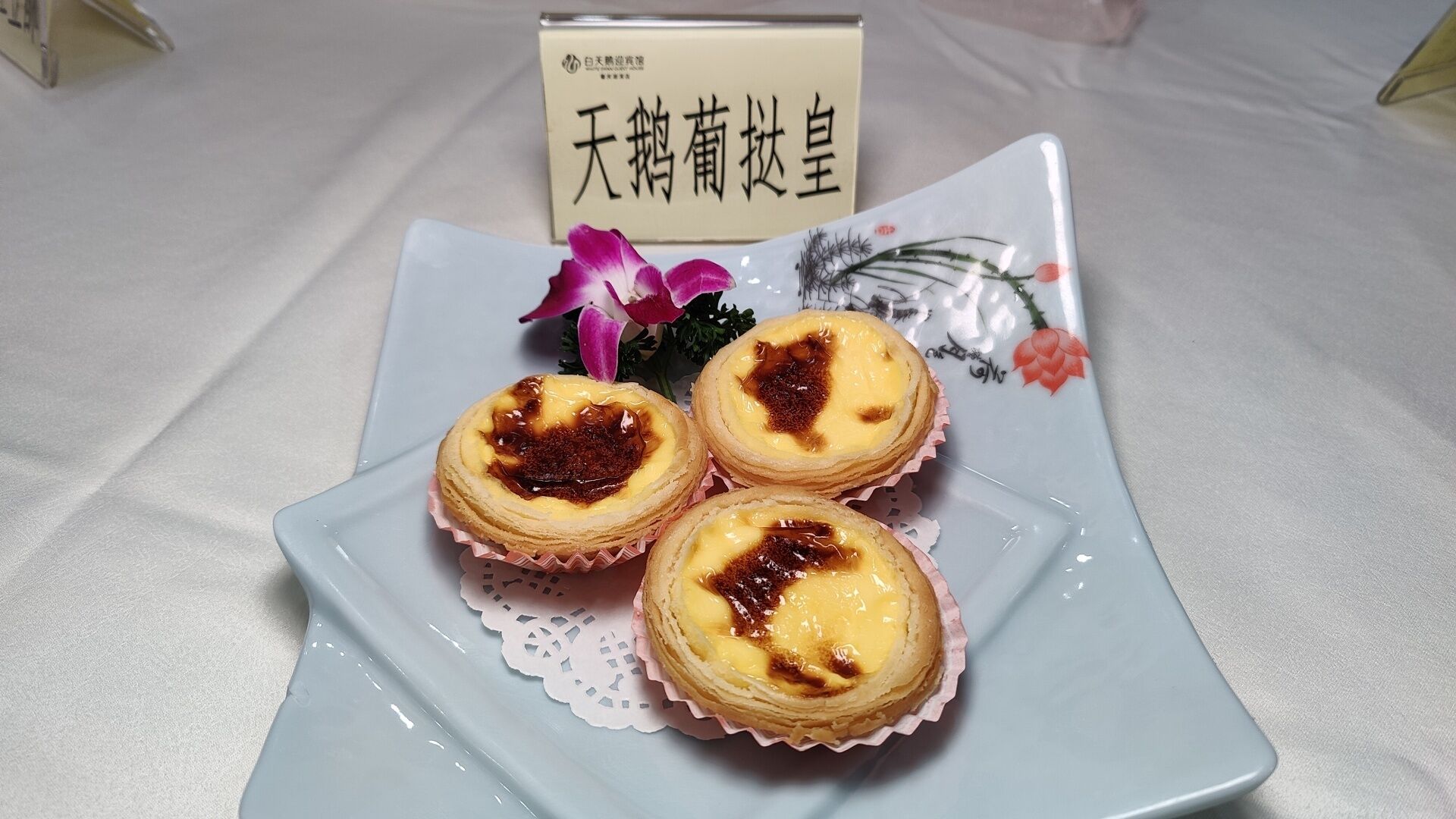 A plate with three custard tarts on a white ceramic plate with a floral design.