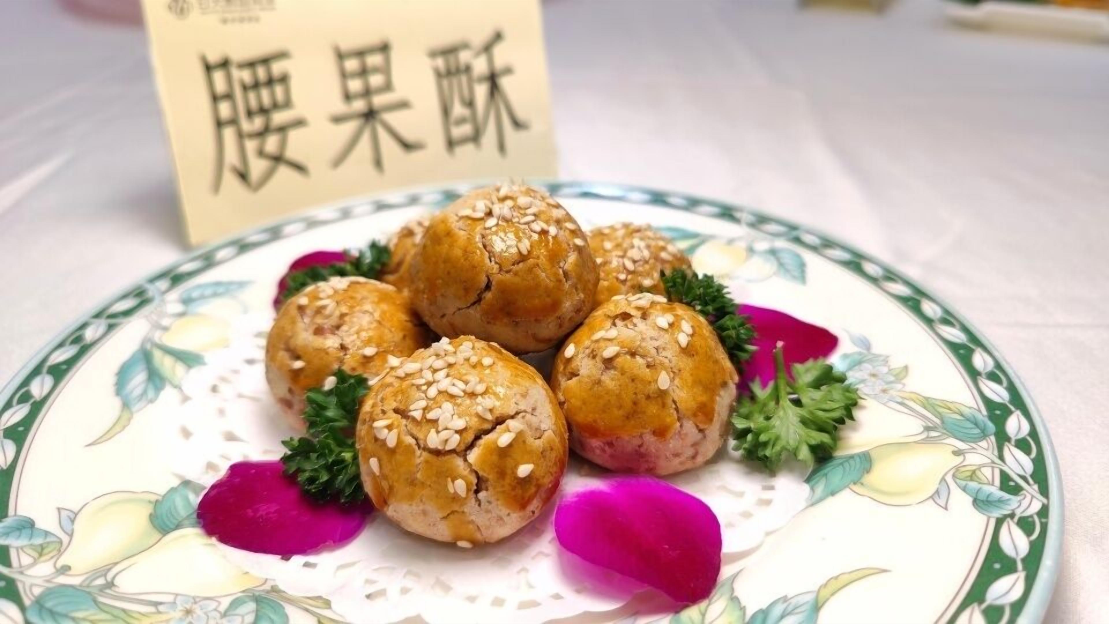 Un plato de bollos cubiertos de semillas de sésamo sobre un plato con estampado floral.