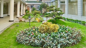 A courtyard with a central garden, surrounding buildings with multiple floors and large windows, and a covered walkway with columns. - White Swan Guest House (Zhaoqing)