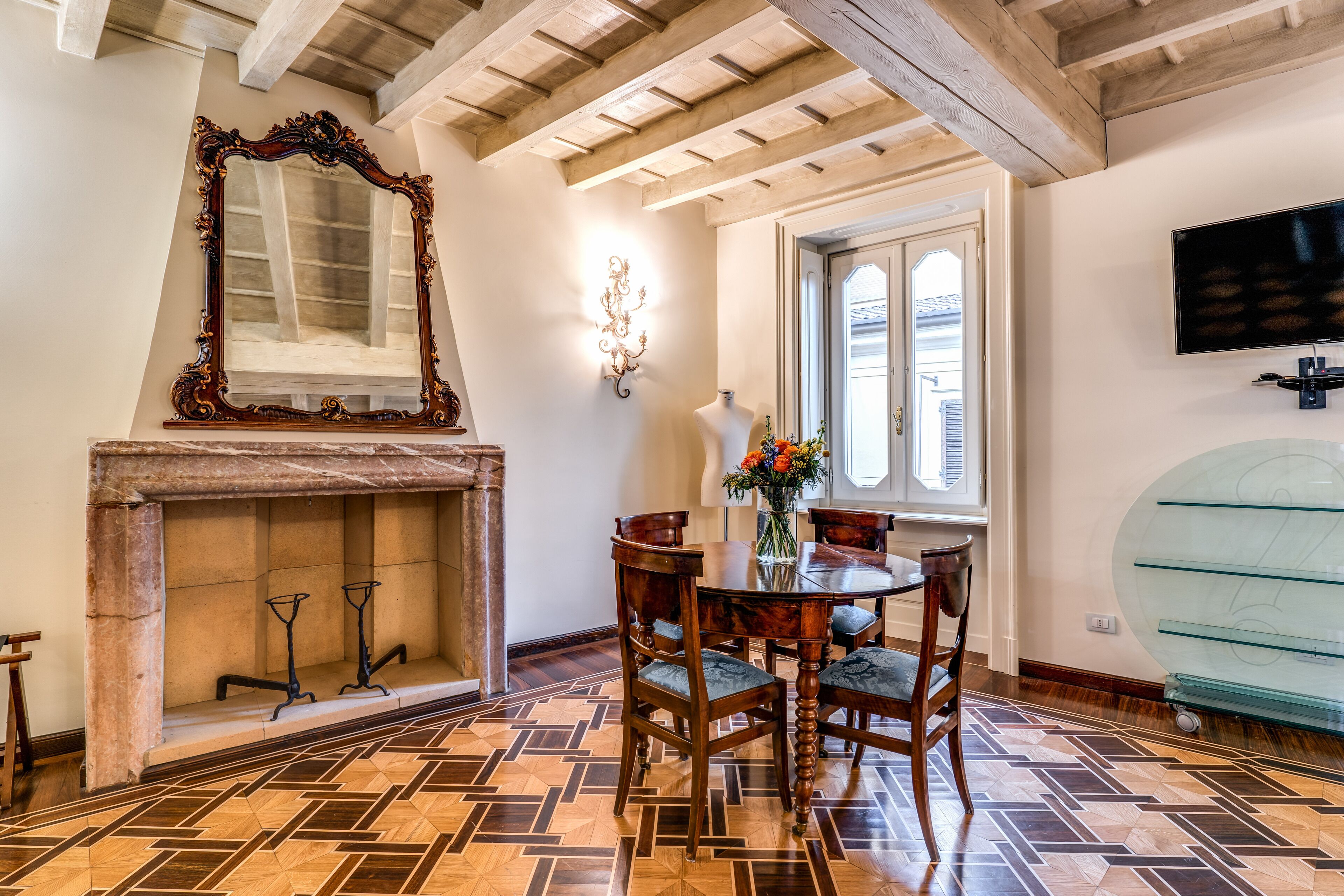 Un comedor con una mesa de madera, sillas, chimenea y un espejo grande.