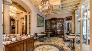 A dining area with a round mosaic table, wooden cabinets, and a globe map on the wall. - Santa Marta Suites (Milan)