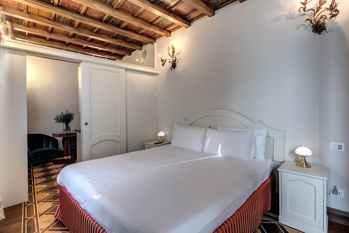 A neatly made bed with white linens, a wooden headboard, and a bedside table with a lamp.