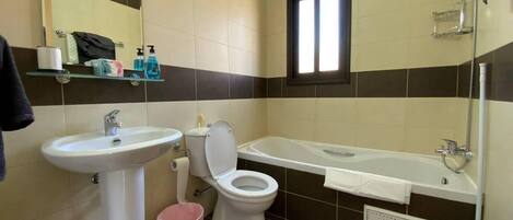 A bathroom with a sink, toilet, and bathtub. There is a window above the bathtub and a mirror above the sink.