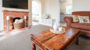 A cozy living room with a brick fireplace, a leather sofa, and a wooden coffee table. - Far Coley Farm &amp; Log Cabin (Stafford)