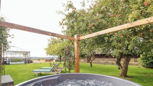 A hot tub in a backyard with a wooden pergola, a lawn, and a tree with apples. - Far Coley Farm &amp; Log Cabin (Stafford)