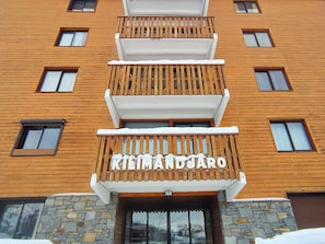 A multi-story building with a wooden facade and balconies. The name 'Klimandžaro' is visible on the front.
