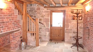 A rustic interior with a wooden staircase, a stone wall, a wooden door, and a metal coat rack. - The Old Cartshed - AWARD WINNING Eco conversion ,sleeps 10, Peak District views SC (Leek)