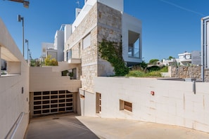 Un bâtiment moderne avec une façade en pierre, un garage et un ciel dégagé.