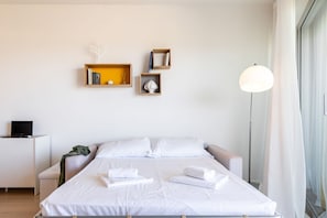 Une chambre d’hôtel bien rangée, avec un lit, des tables de chevet, un bureau et une lampe.
